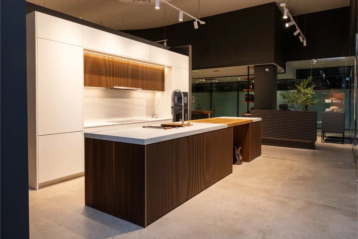Rastelli-LA-White-Kitchen Modern Italian kitchen display with white flat-panel cabinetry and fluted walnut island at Rastelli's Los Angeles kitchen showroom