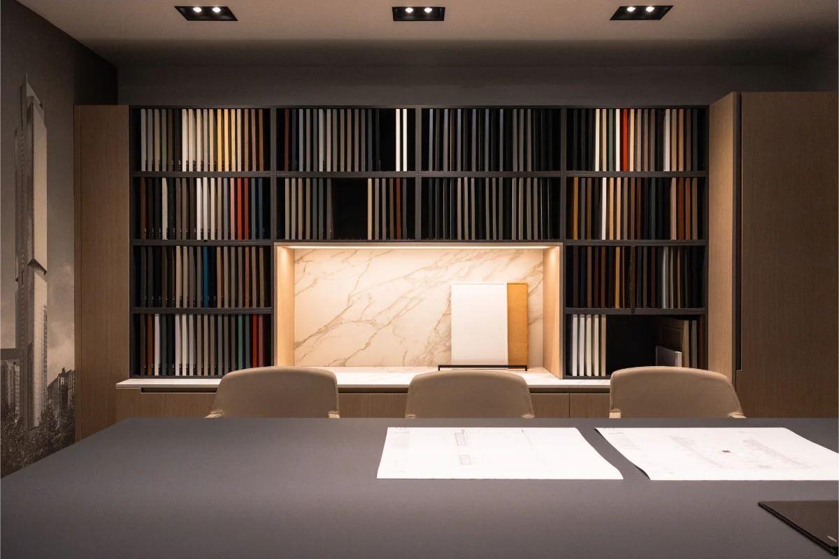 Design consultation room at Rastelli's Los Angeles showroom featuring a full wall of door and finish samples, a backlit marble display, and a large table with architectural plans 